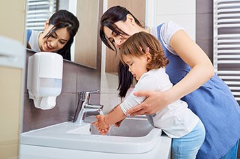 mother helping daughter wash her hands